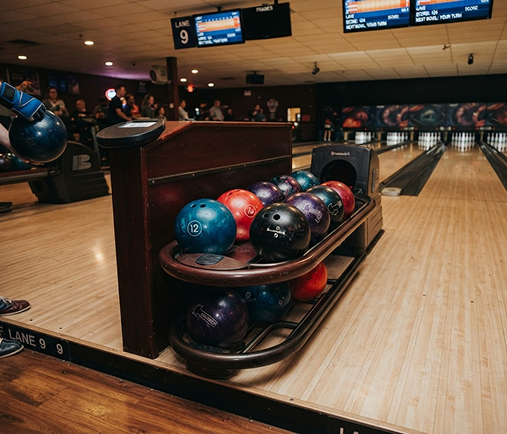 A rack of colorful bowling balls beside the lanes